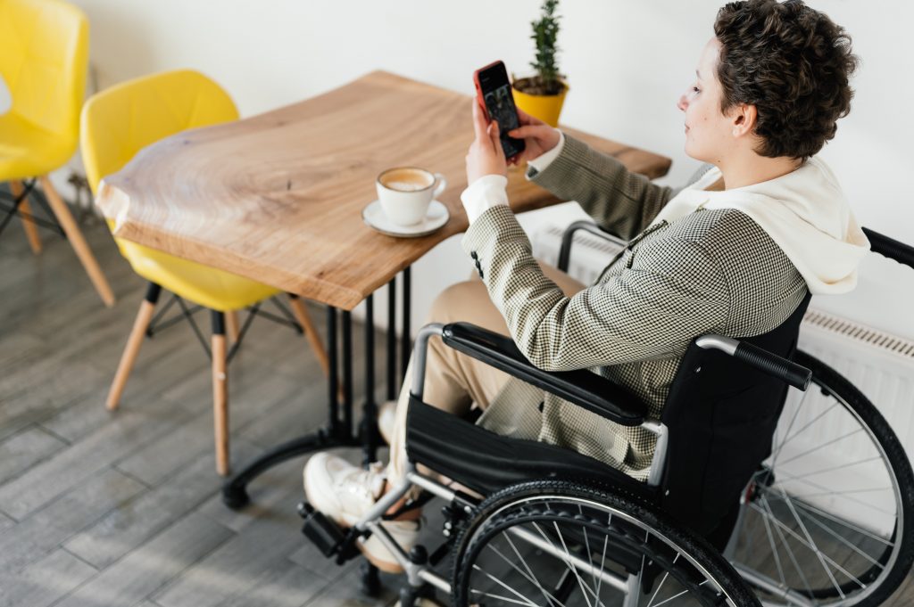 Occupational Therapist Sunshine Coast - woman in wheelchair at table using mobile phone